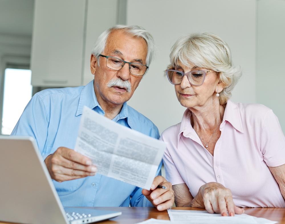 An older couple looking at insurance paperwork and wondering what an adverse benefit determination means.